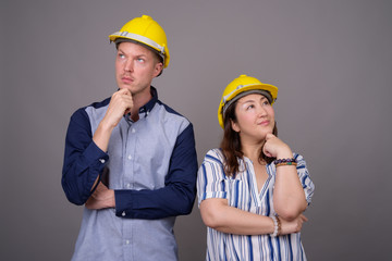 Businessman and mature Asian businesswoman wearing hardhat