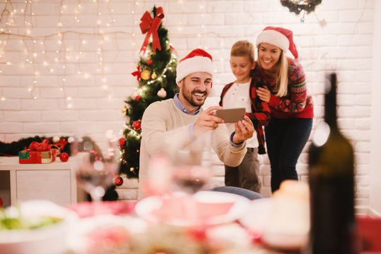 Father taking photo of him and his family. In front Christmas table. Christmas holidays concept.