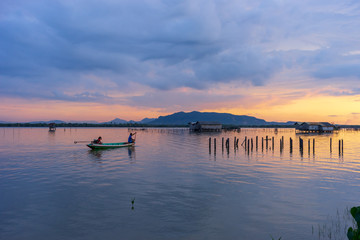 Fototapeta na wymiar Twilight sky during sunset in Songkhla Lake with view of mountain, cloudy sky and small fisherman hut in the middle.