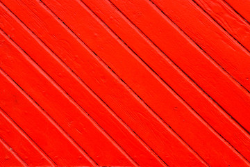 Old grungy and weathered red orange painted wooden wall plank in diagonal to the frame as simple...