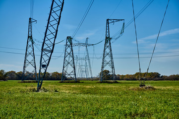 Air high-voltage transmission lines of electric energy over long distances. Overhead lines lay electricity above ground through wires attached to supports. Support, wires and blue sky without clouds