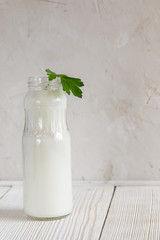 One full opened bottle of kefir with green sprig of parsley staying on white background.