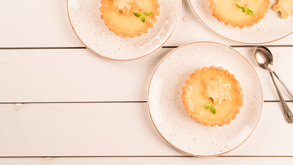 a homemade dessert of lemon flavour tartlets, on white wooden backdrop © Olga Barilo