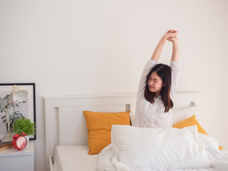 asian woman stretching in bed after wake up