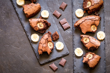 chocolate brownie with banana on shale plates on dark background