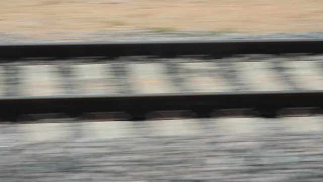Rails and sleepers flickering during the movement of the train. Side view of railway from fast train in city from the train window