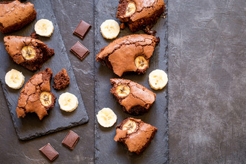 chocolate brownie with banana on shale plates on dark background