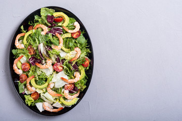 Mix of salad with shrimps , avocado and cherry tomatoes . Healthy food background