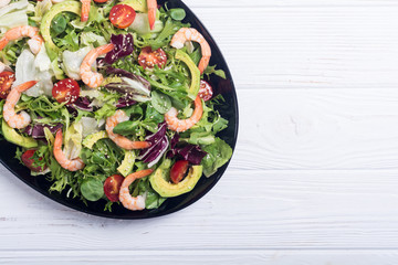 Mix of salad with shrimps , avocado and cherry tomatoes . Healthy food background