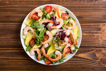 Mix of salad with shrimps , avocado and cherry tomatoes . Healthy food background