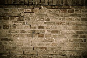Detail of old and weathered grungy brown brick wall with desaturated colors marked by the long exposure to the elements as surface texture background with vignetting.