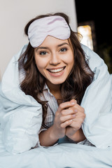 beautiful happy girl in sleeping mask lying in bed