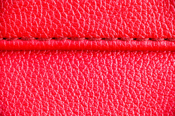 Two layers of red leather textile sewed stitched tightly together under high magnification close detail photography as surface texture background.