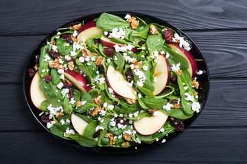 Autumn spinach salad with apple , cheese , walnut and dried cranberry . Healthy vegetarian food