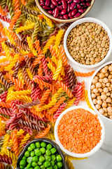 Trend healthy food, vegan diet concept. Multi colored legume pasta with raw beans. Beans, chickpeas, green peas, lentils. Copy space top view