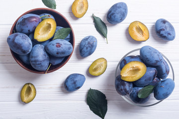 Fresh plums in bowl on wooden table