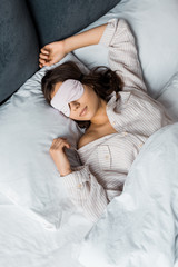 attractive young woman sleeping in eye mask in bed