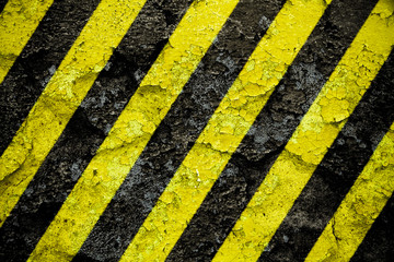 Warning sign yellow and black stripes pattern painted over concrete cement wall facade with peeling...