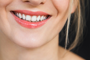 Detail on a gorgeous smile of a beautiful happy blonde woman. Her lips are painted with bright red lipstick, skin is soft and natural and do not miss her stunning white teeth.