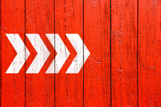 White directional arrow signs pointing direction painted on a red wood wall signboard texture background.