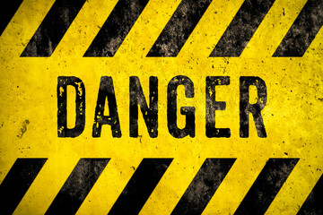 DANGER warning sign word text as stencil with yellow and black stripes painted over concrete wall...