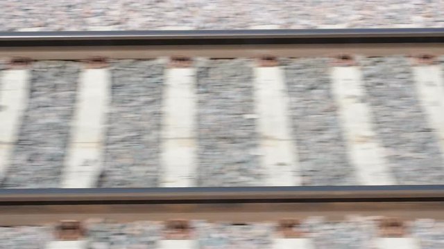 Rails and sleepers flickering during the movement of the train. Side view of railway from fast train in city from the train window