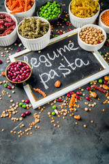 Trend healthy food, vegan diet concept. Multi colored legume pasta with raw beans. Beans, chickpeas, green peas, lentils. Copy space top view