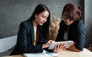 The businesswomen talking business together,using tablet,with serious feeling,at office