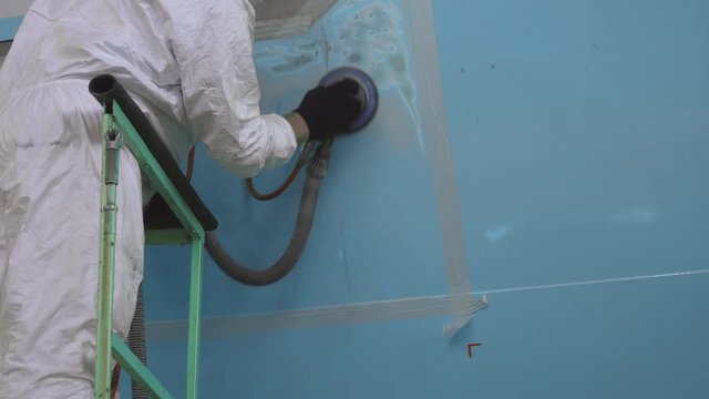 Painting the aircraft at the factory. The engineer repairing the aircraft. Maintenance of passenger aircraft. Repair of an aircraft wing. Passenger plane in the hangar in the repair. 4K