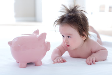 Baby boy with a piggy bank in childcare costs or savings theme