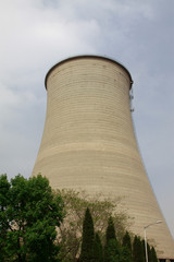 heavy industrial water cooling tower and the green tree