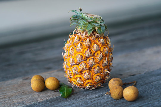 A pineapple and longan fruits on a wooden table
