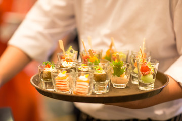 Waiters carrying plates with meat dish at a wedding.Crab meat appetizer served on Cucumber slices.Food arrangements for welcoming the guest of honor.Waiter serving cocktails on a tray.