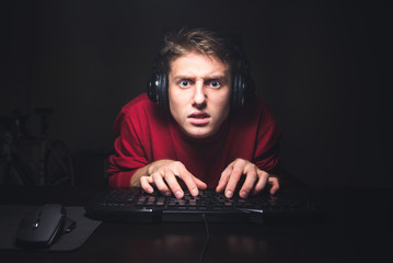 Focused gamer portrait looking at the game and using a computer keyboard. A concentrated young man...