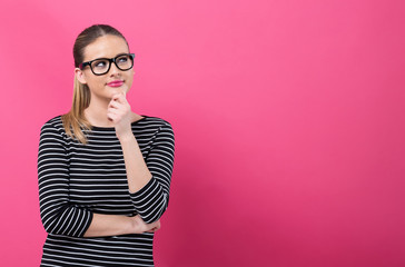 Young woman in a thoughtful pose on a pink background