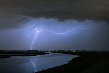 Horizontal and vertical lightning bolts from a severe thunderstorm over a lake in the western part of Holland
