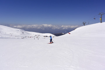 Fototapeta na wymiar A boy in a blue ski jumpsuit skiing from the snowy mountains of the Sierra Nevada