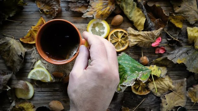 hand with cup of tea on autumnal wood background