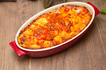 Italian food. Hot tasty freshly baked lasagna served with basil herb on wooden table.
