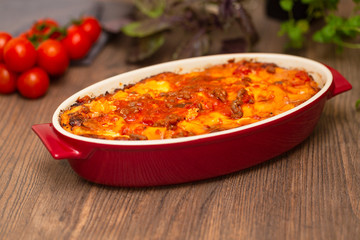 Italian food. Hot tasty freshly baked lasagna served with basil herb on wooden table.
