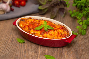 Italian food. Hot tasty freshly baked lasagna served with basil herb on wooden table.