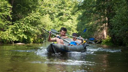 Athlete men in kayak with oars on wild river