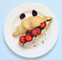 Croissant with cream cheese, strawberries and basil for breakfast, top view 