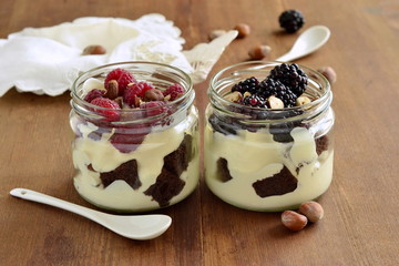 Dessert with chocolate biscuit, cream, hazelnut and fresh berries in glass jars, trifle