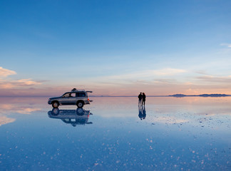 Exciting scenery of spacious Salar de Uyuni with couple and car