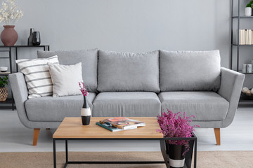 Real photo of a grey sofa, coffee table and lavender flower in a living room interior