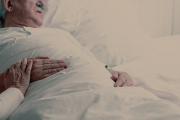 Senior man with terminal illness laying in hospital bed, photo with copy space