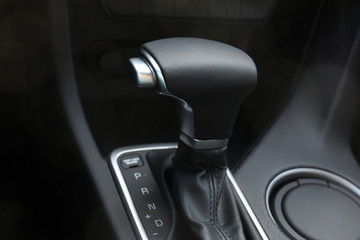 Car interior. Black leather automatic gearbox with chrome button and round ashtray 