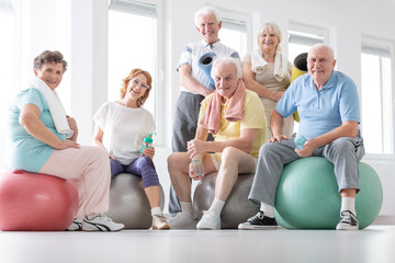 Happy senior people sitting on balls after physical classes in the studio