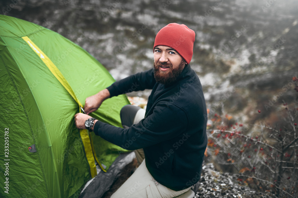 Wall mural overhead shot of traveler man with beard pitch tent camping gear outdoor in mountain. male hiking in